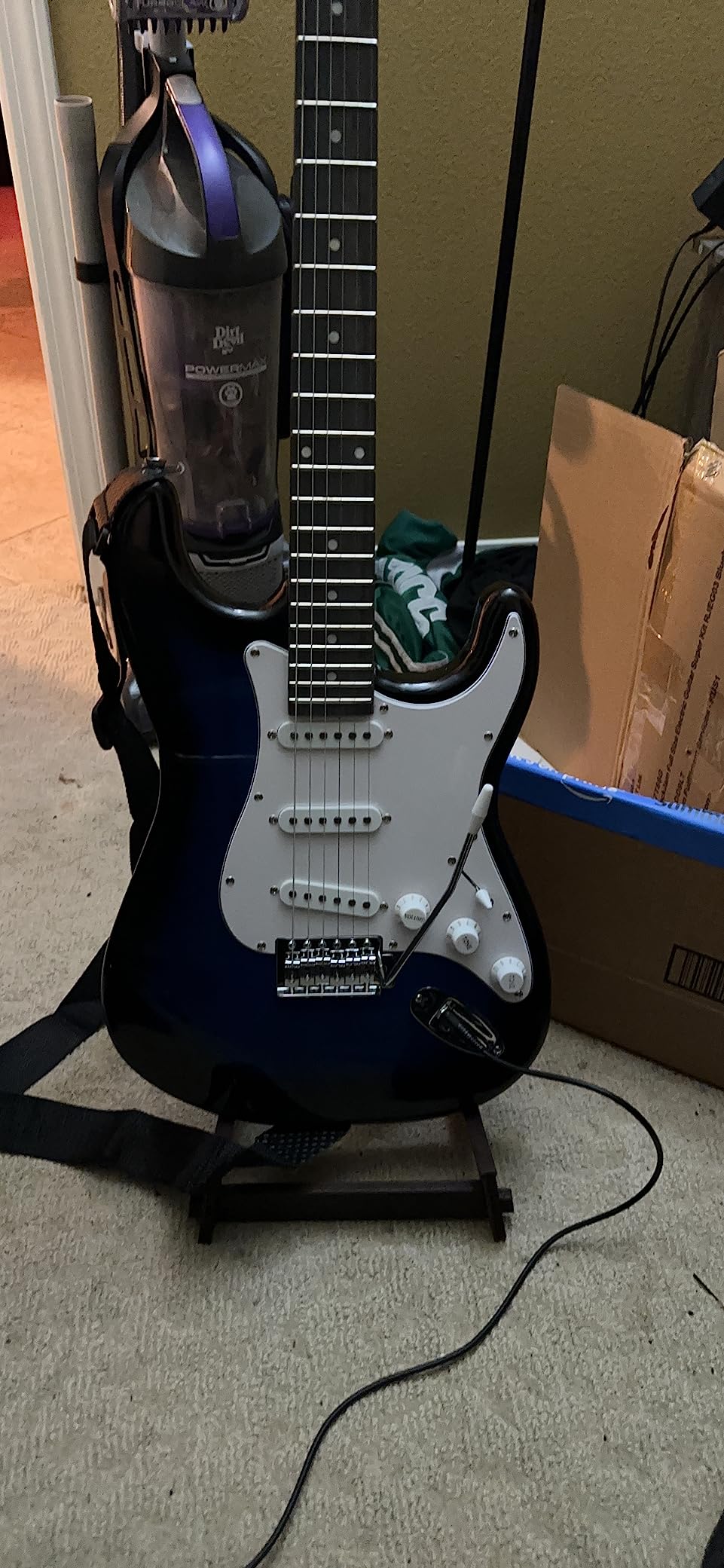 RockJam blue burst electric guitar on a folding stand with the strap fitted and the instrument cable plugged into the jack